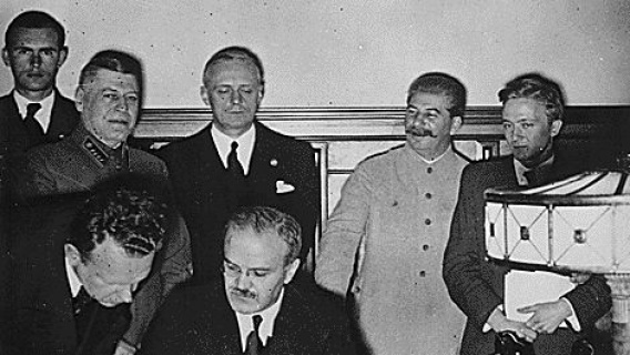 The pact was signed by Molotov (seated) and Ribbentrop (standing 3rd from left)